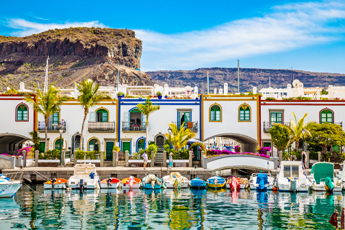 Puerto de Mogán op Gran Canaria met witte huizen, kleurrijke bloemen en een kanaal met boten langs de sfeervolle straatjes.